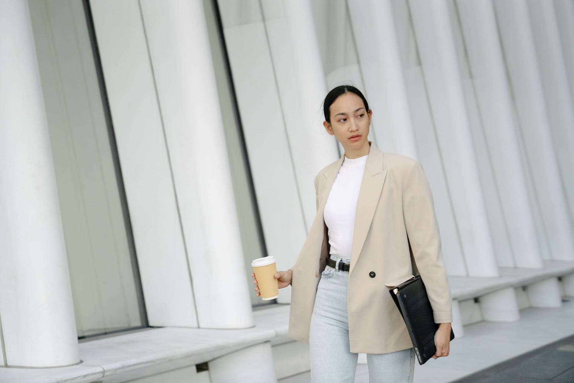 serious ethnic woman with takeaway coffee and folder