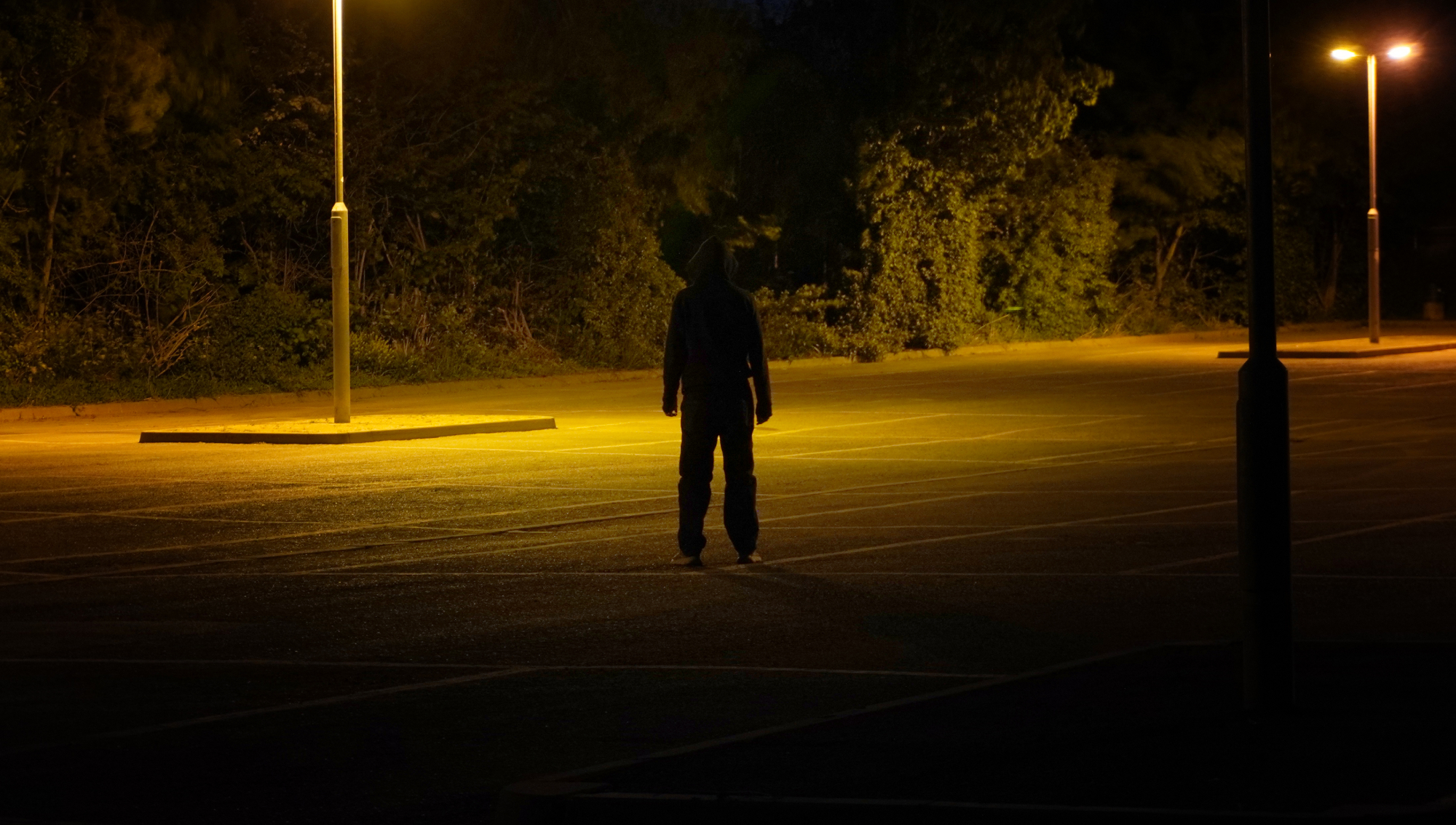 A mysterious hooded figure, standing with back to camera