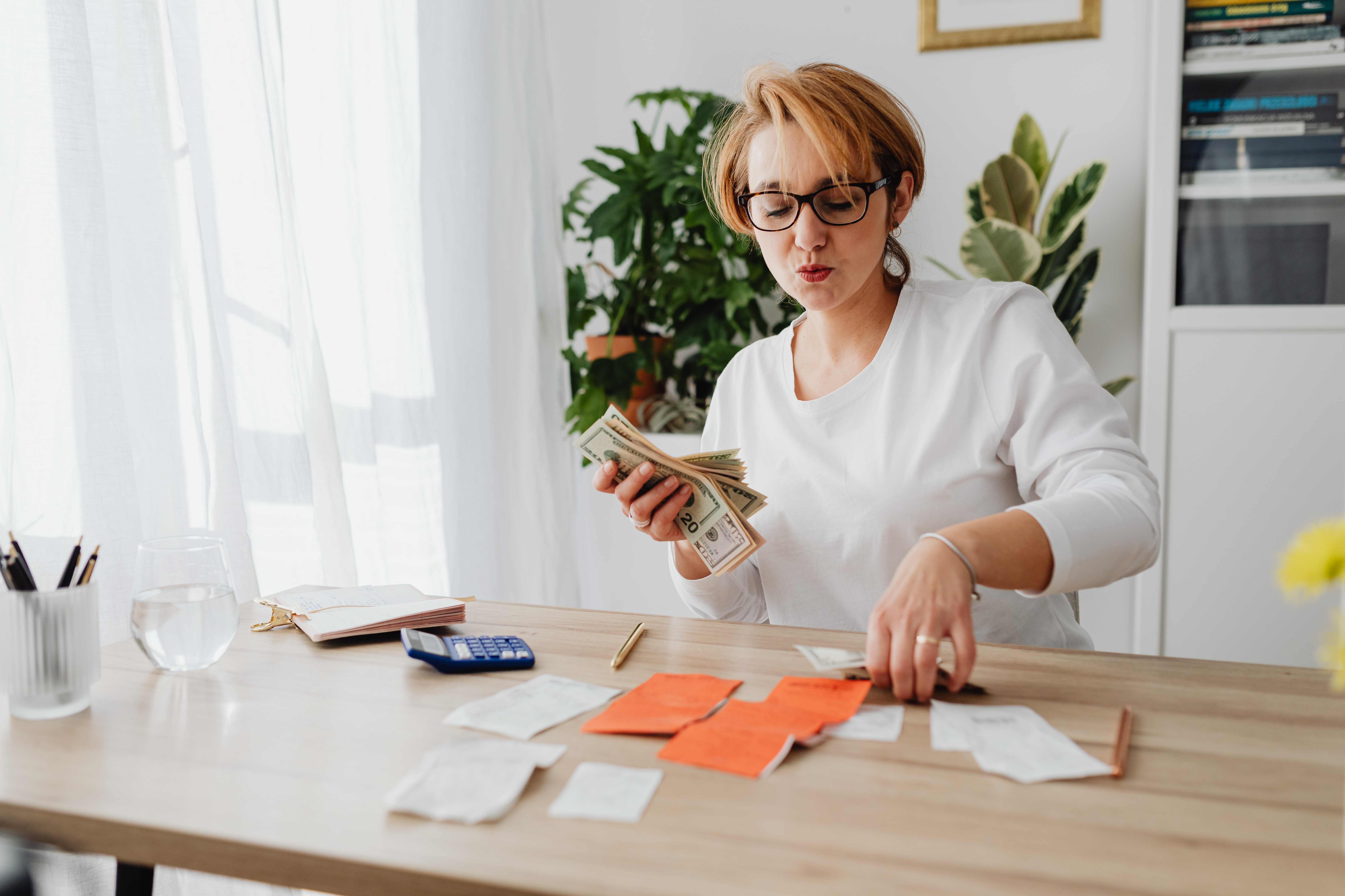 A woman budgeting with cash and receipts