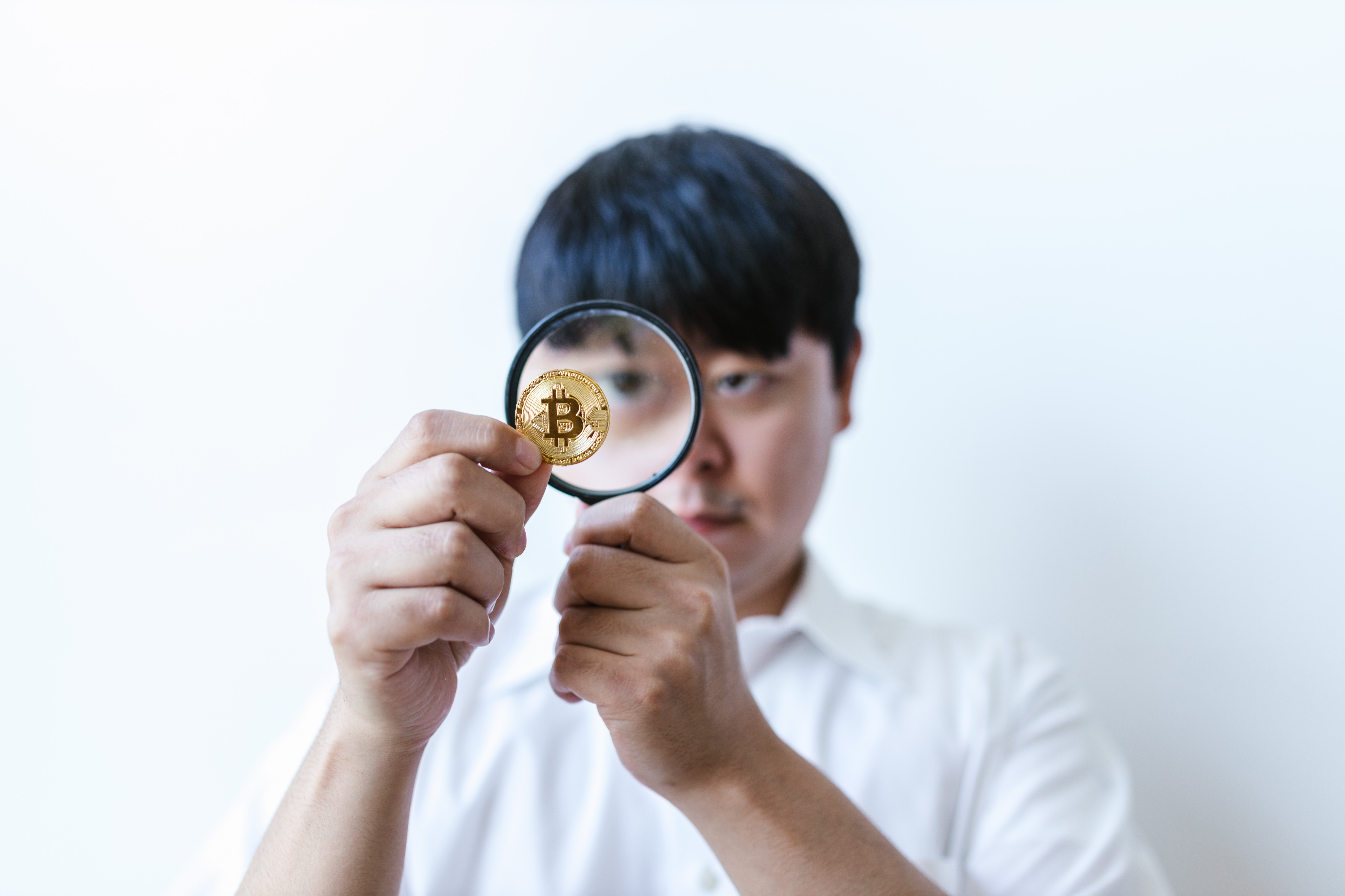 A man looking at a coin through a magnifying glass