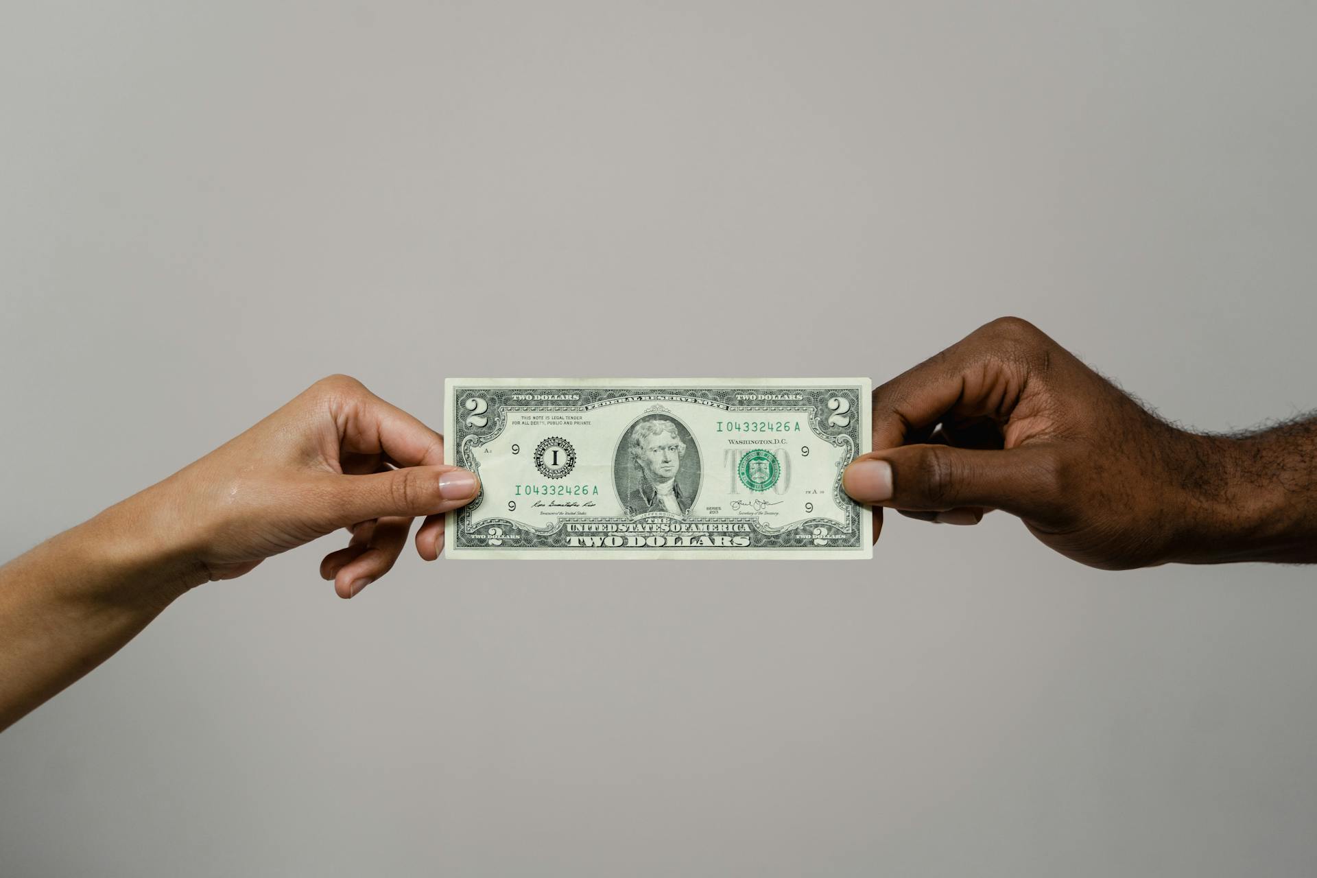 Hands holding two dollars