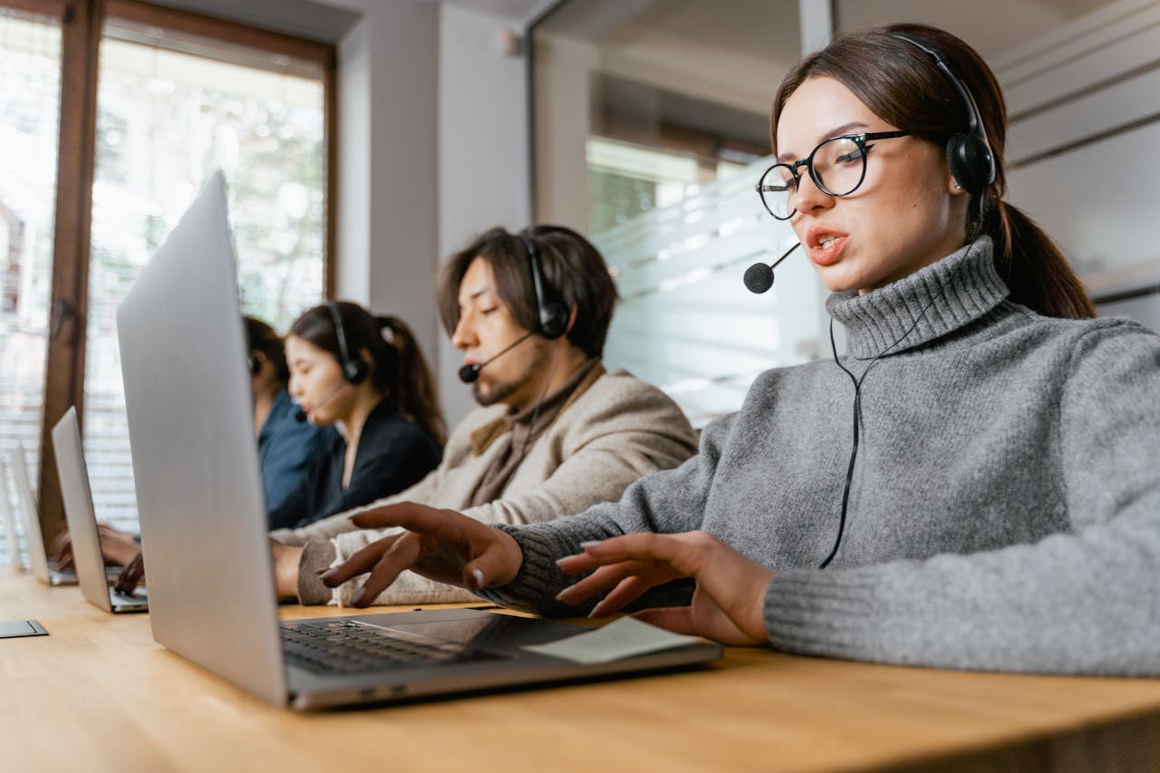 A Woman with Laptop and Headset Attending to a Call