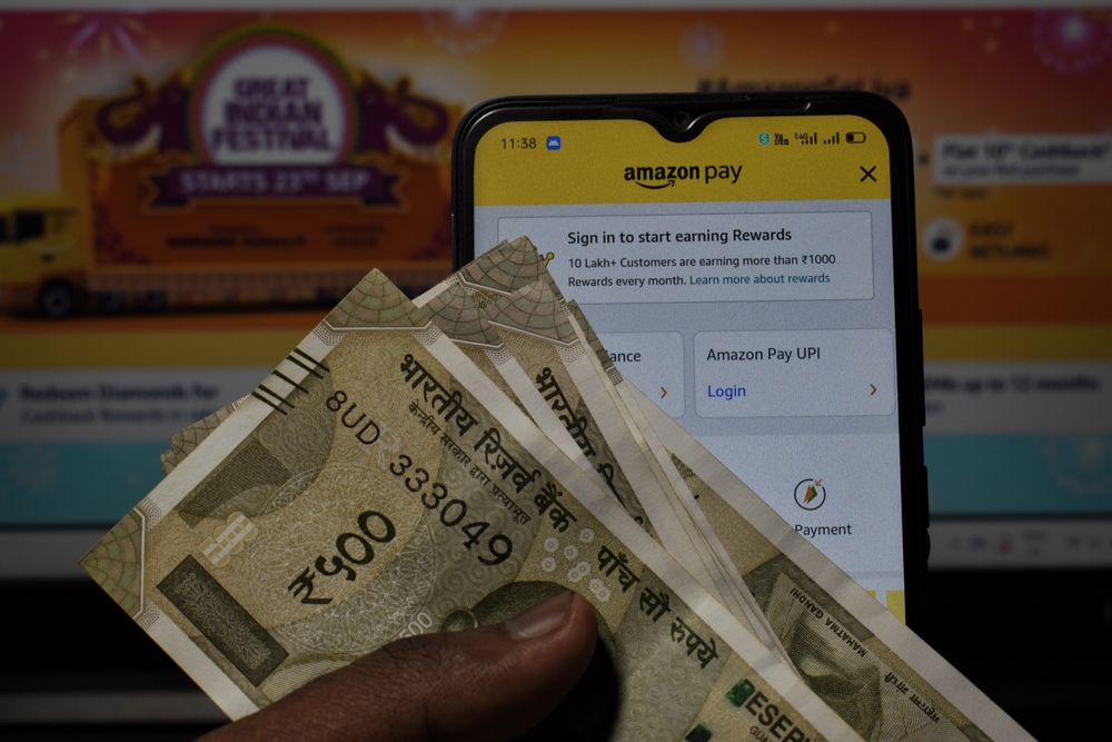 Customer viewing Amazon pay on mobile phone with Amazon webpage background