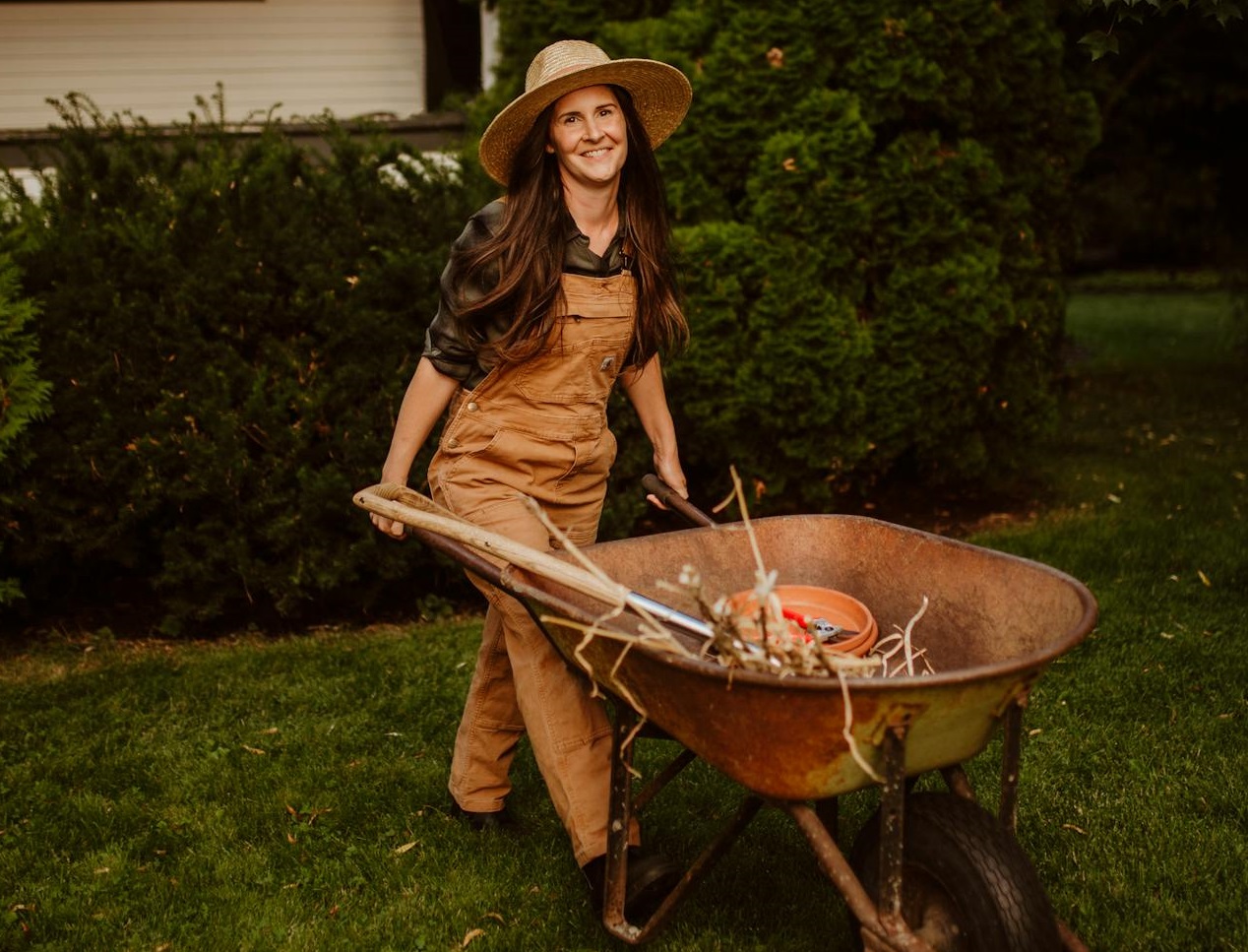 Gardener Pushing Wheelbarrow in Yard.