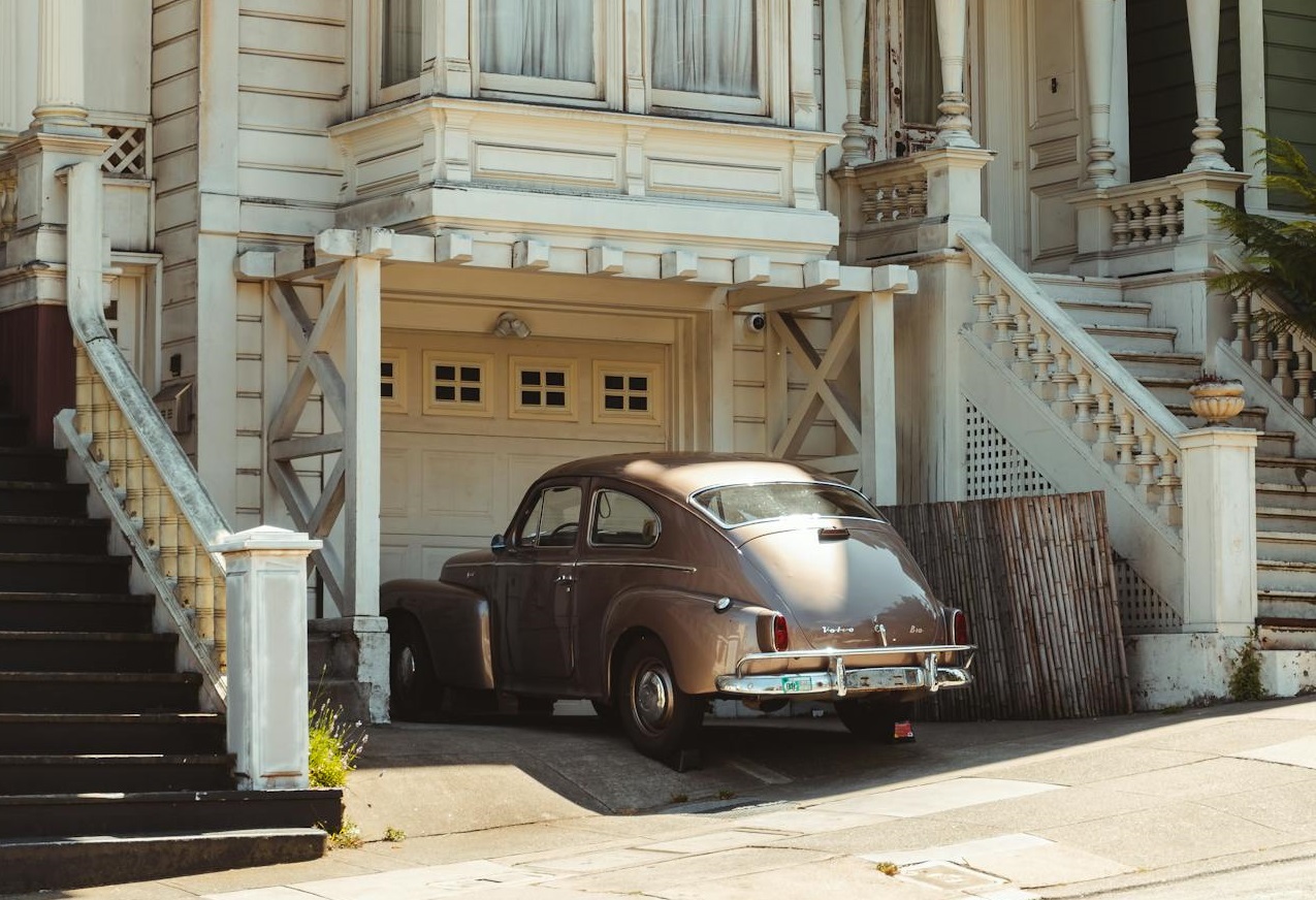 Old fashioned car parked near aged classic house