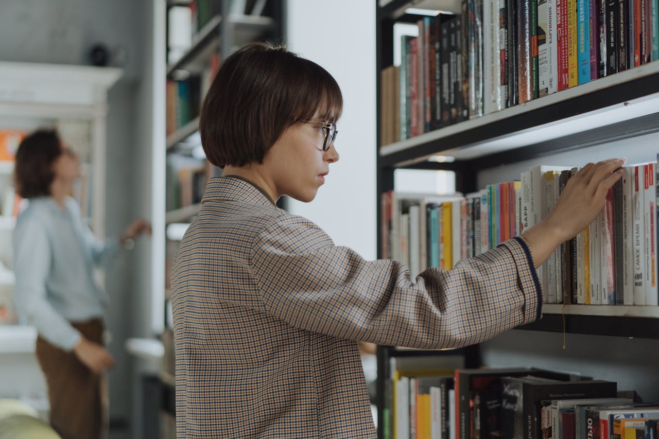 Woman Standing in Front of Book Shelf And Browsing