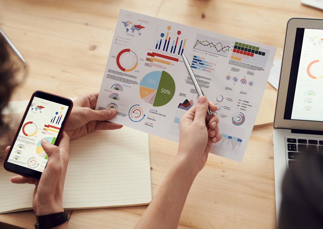 Two colleagues analyzing financial data reports on laptop with charts