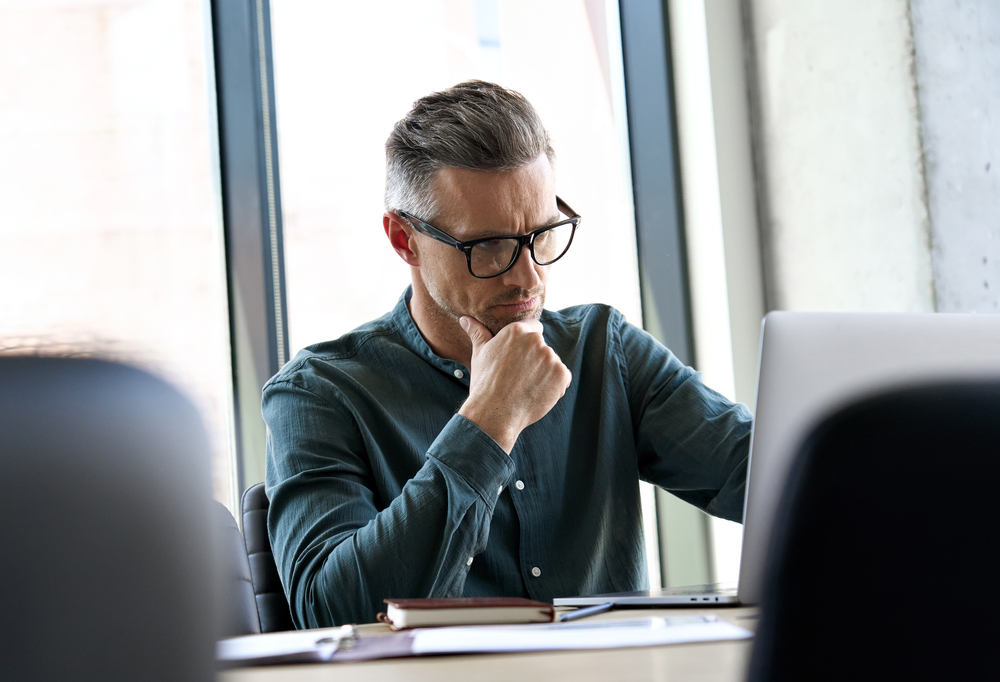 Serious busy elegant mature businessman thinking of online business