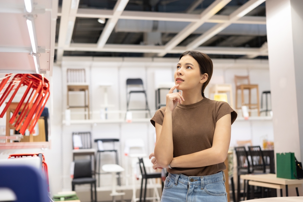 Young beautiful woman choosing the right chair furniture for her house