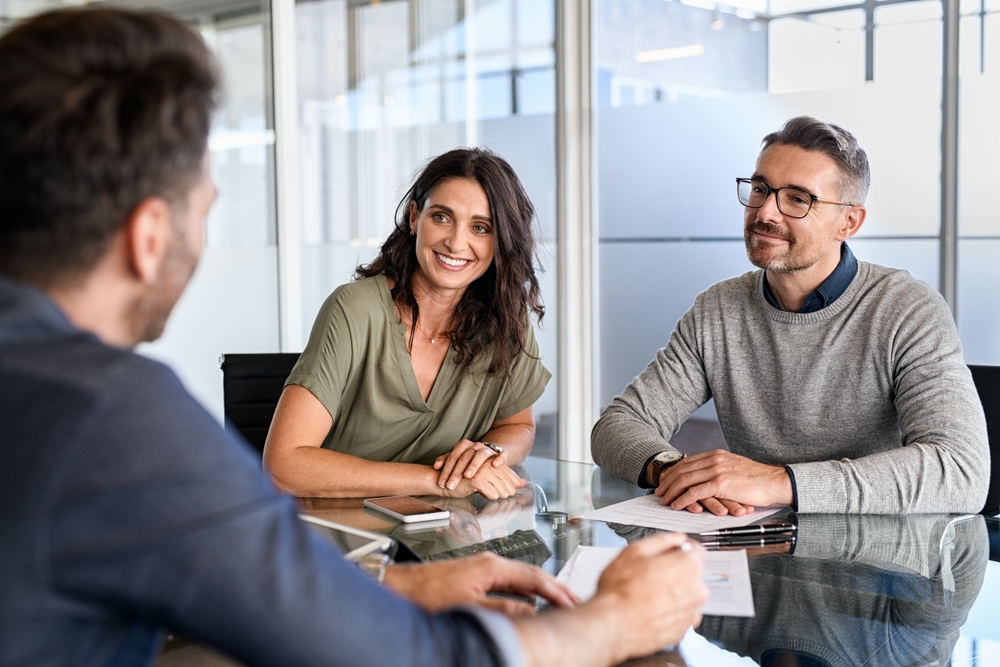 Smiling mature couple meeting with bank manager for investment