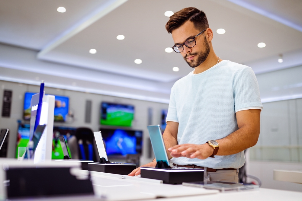 Happy young man trying out new smart phone, digital devices