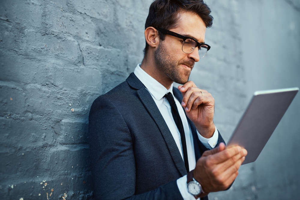 Portrait Photo of businessman thinking while leaning on a gray wall