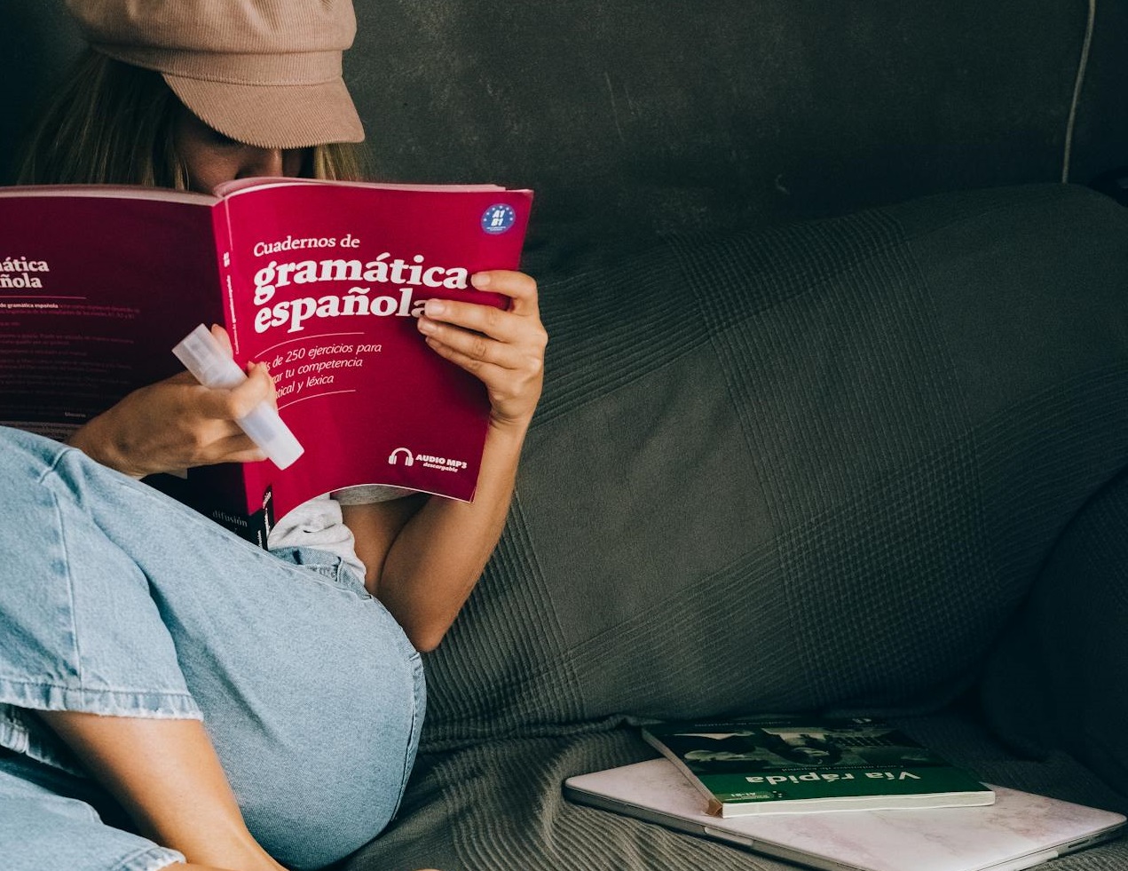 A Woman Sitting on the Couch while Reading a Book