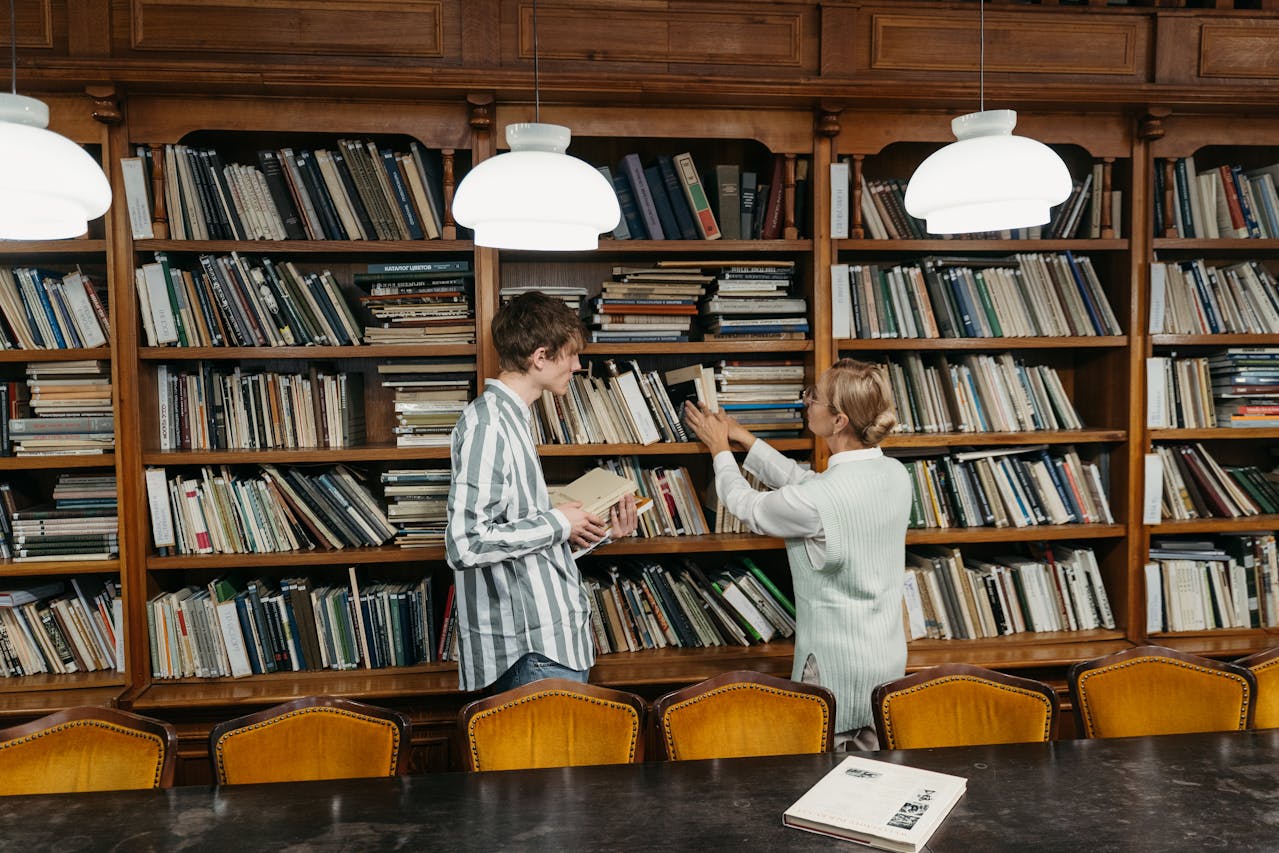 A man and a woman standing beside a bookcase