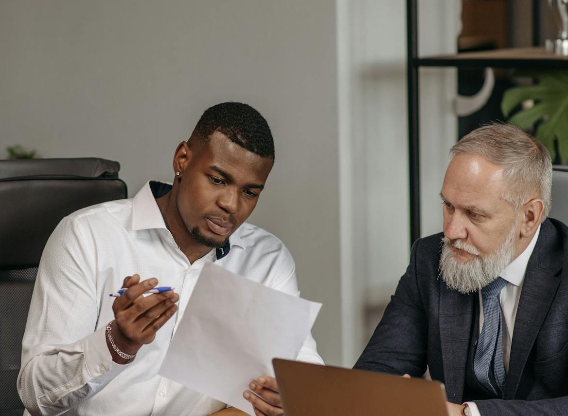This image shows two men in a professional setting, engaged in a discussion