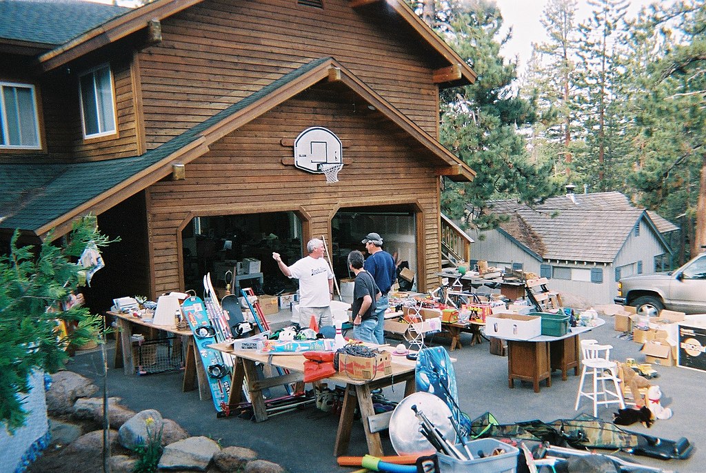 Photo of lively yard sale taking place in the driveway of a house