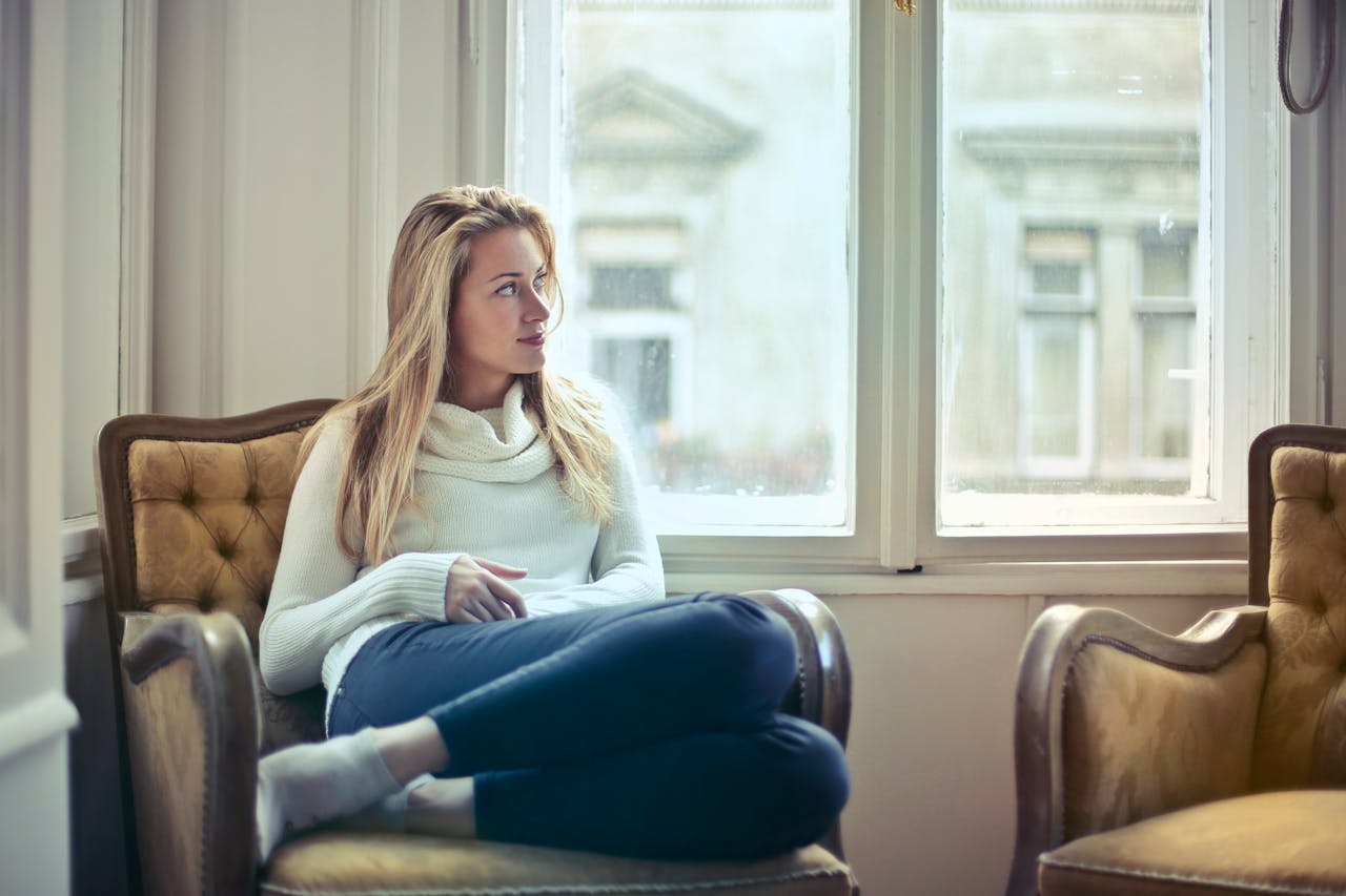 Photography of Woman  Sitting on Chair Near Window