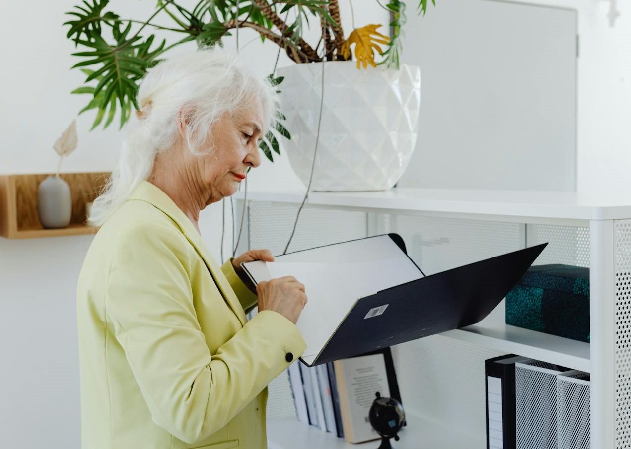 Elderly Woman Holding Binder in the Office