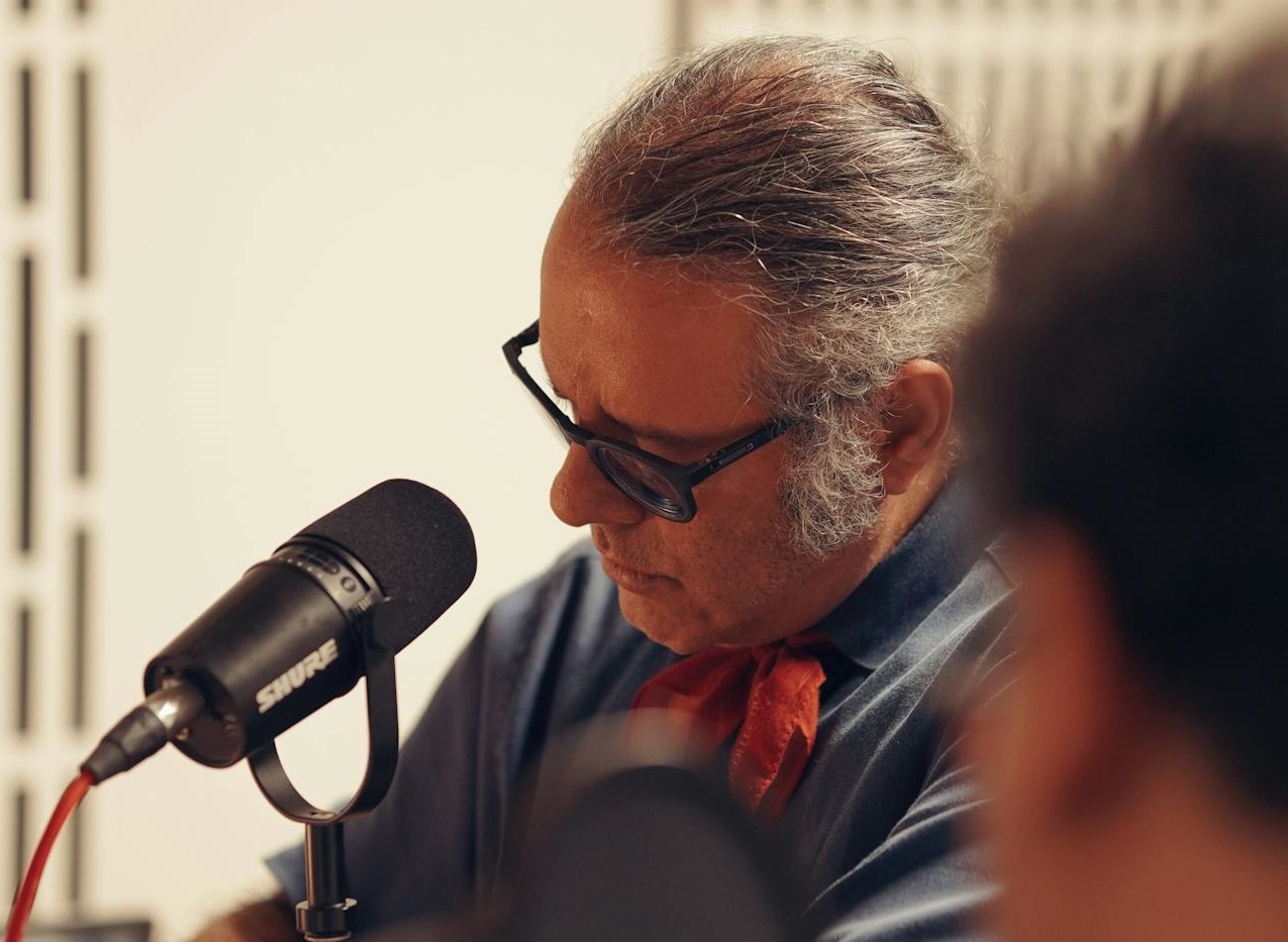 Man Speaking into a Microphone on a Table