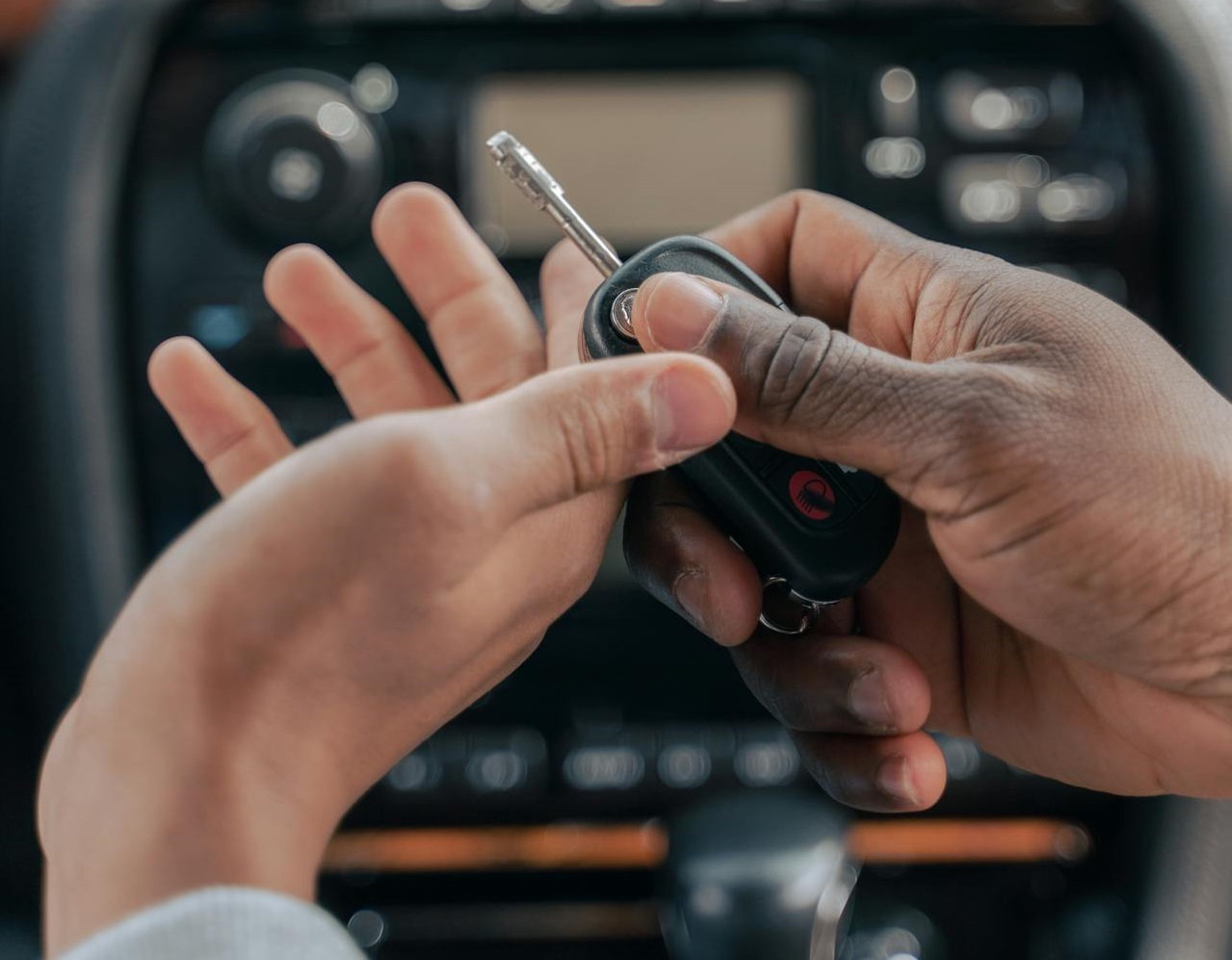 Person giving a car key to other person.