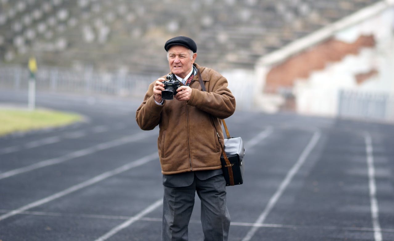 An older man is taking a picture.