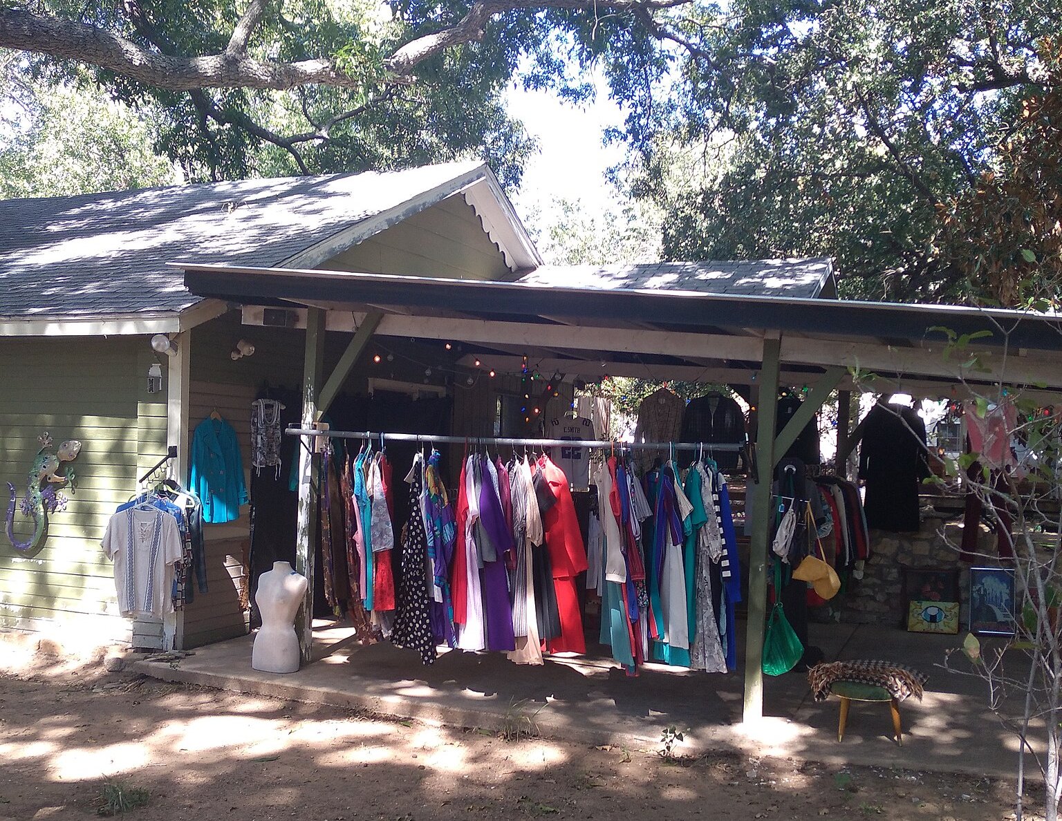Outdoor setup for a garage or yard sale under the shade of large trees