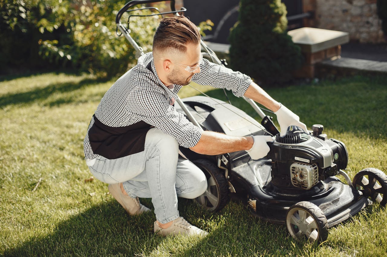 Man in Black and White Long Sleeve Shirt Holding Black Lawn Mower