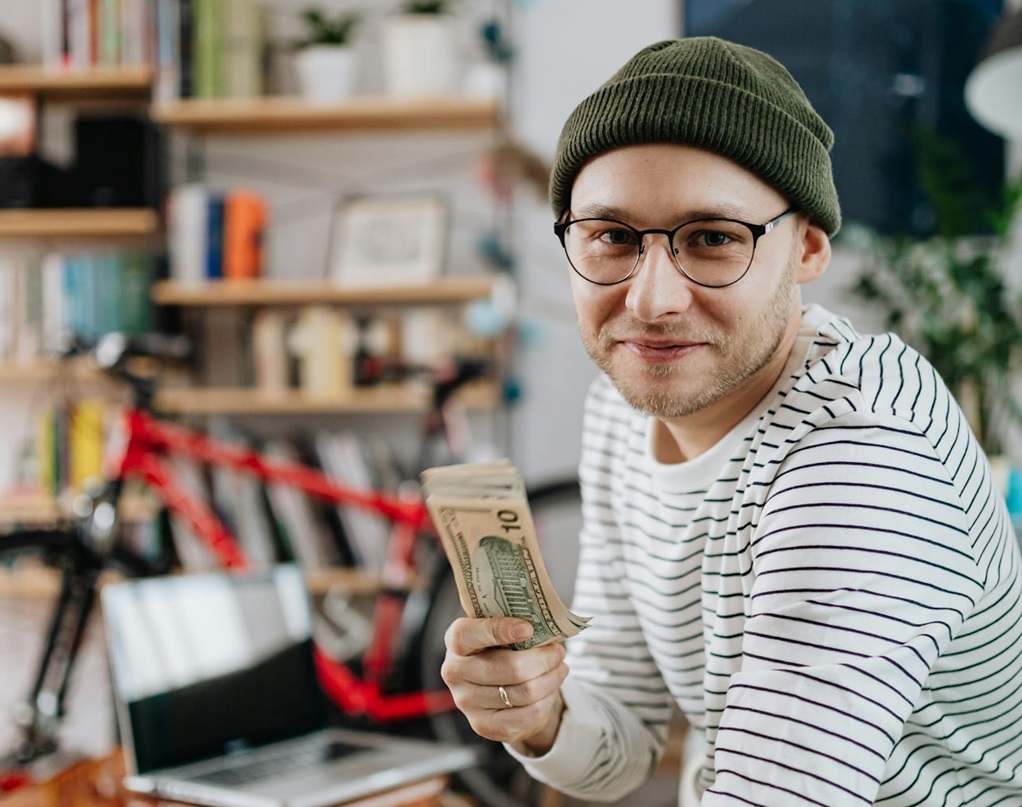 A Man Smiling at the Camera holding money.