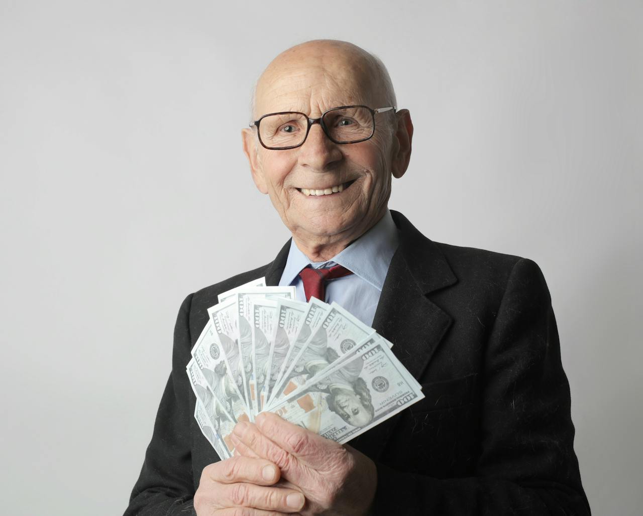 Senior Man In Black Suit Holding Dollar Bills