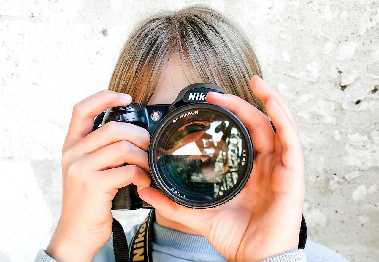 A Young Girl in Blue Sweater Holding a Black Camera
