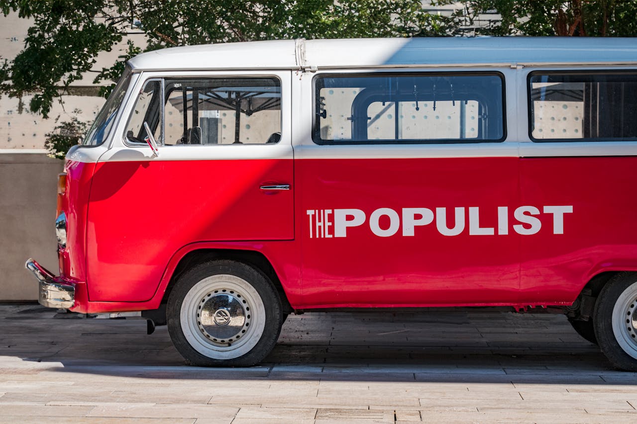 A close-up photo of a Red Volkswagen Type 2 Bus parked on a city street