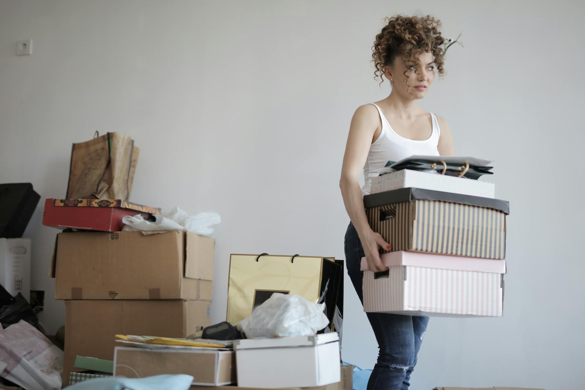 Concentrated woman carrying stack of cardboard boxes