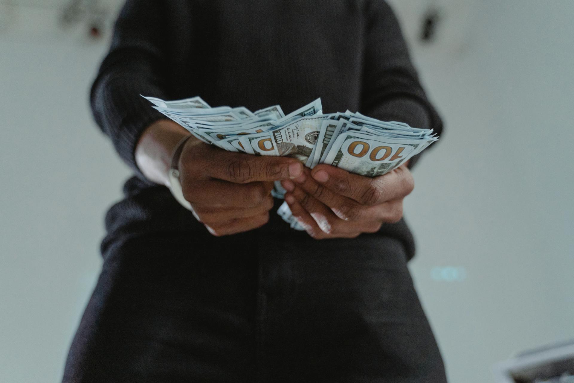 Close-Up Photo of a Person's Hands Holding Dollars