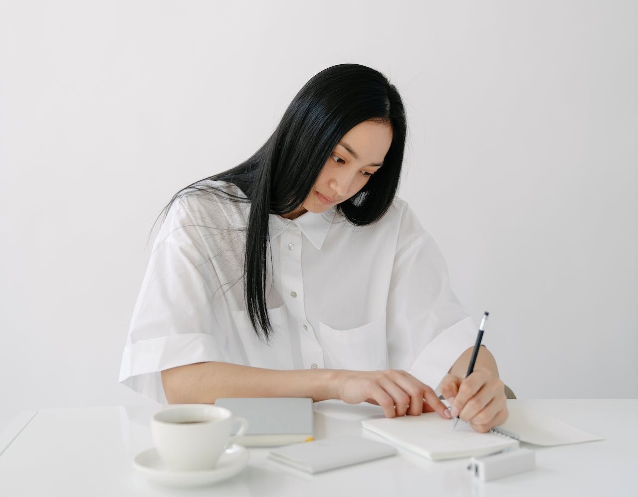 Woman at office is writing her tasks at notebook.