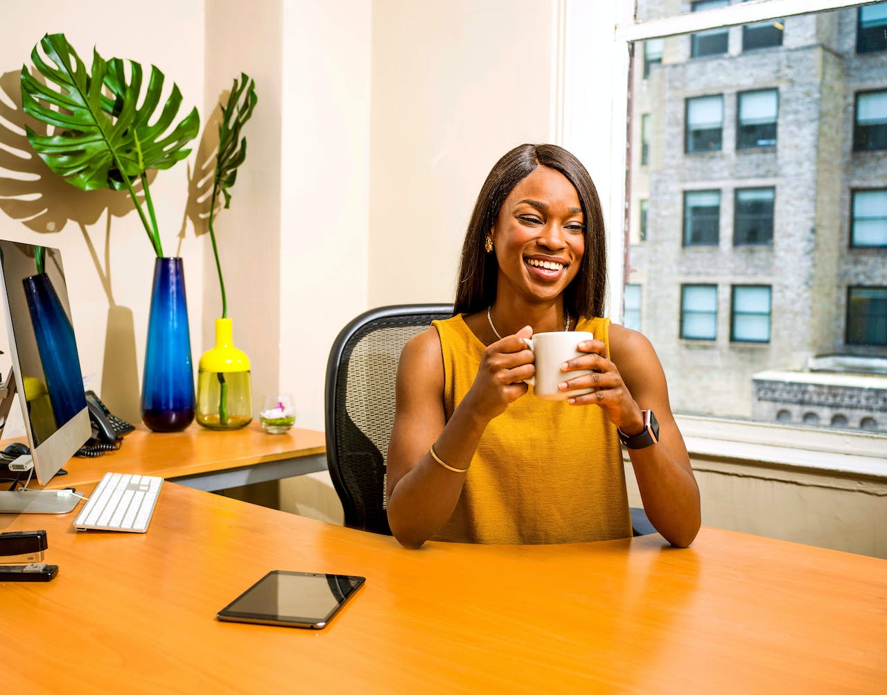 Smiling woman drinking coffee at office.