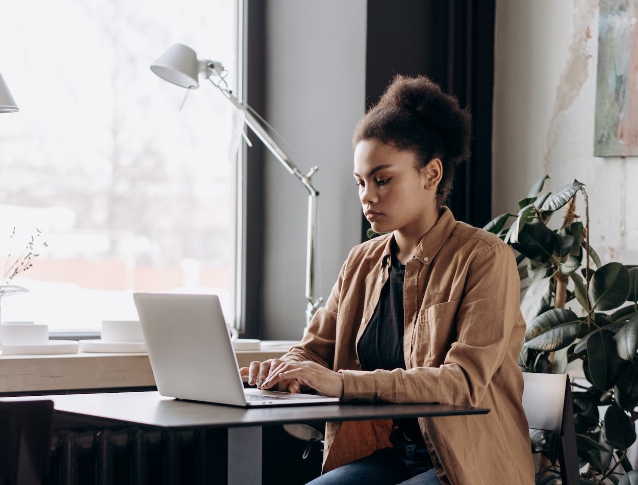 Woman working on her laptop beside window.
