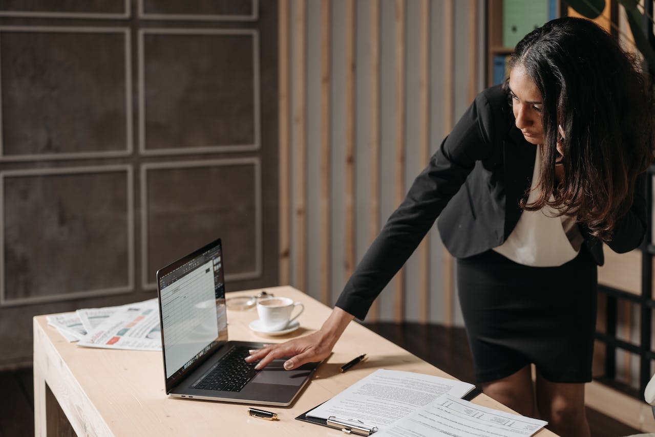 Woman in office working on laptop and talking on the cell phone.