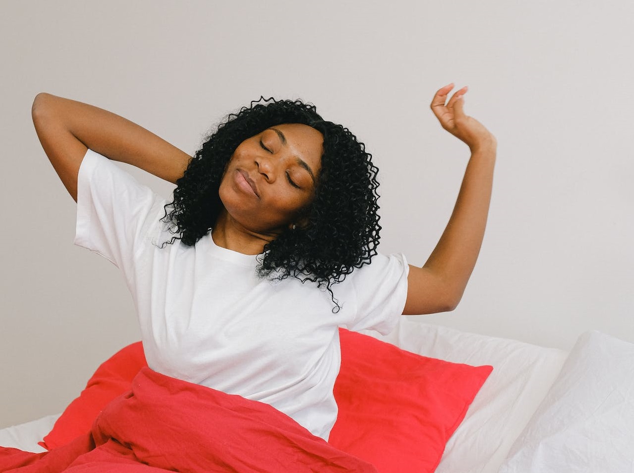 Young woman is waking up from sleeping at her bed.