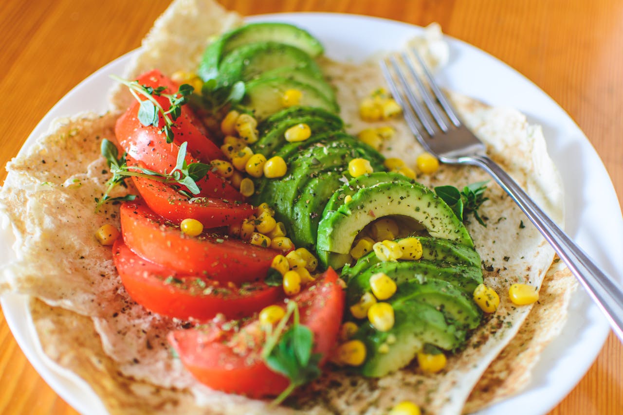 Sliced tomato and avocado on white plate.