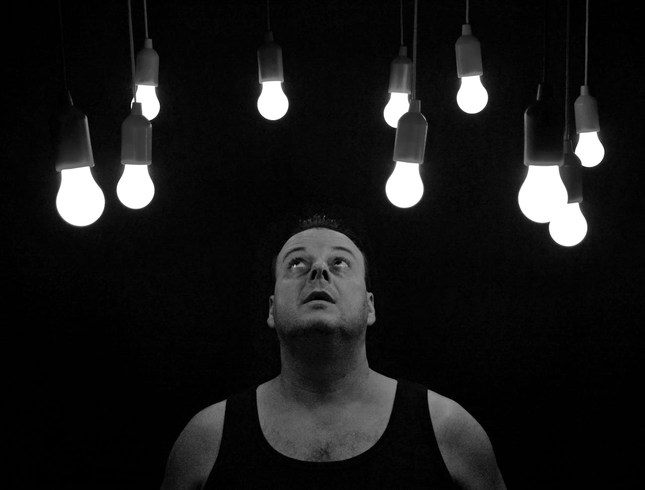Man looking up at illuminated light bulbs.