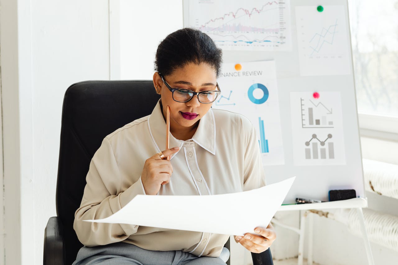 Woman holding a white paper in office.