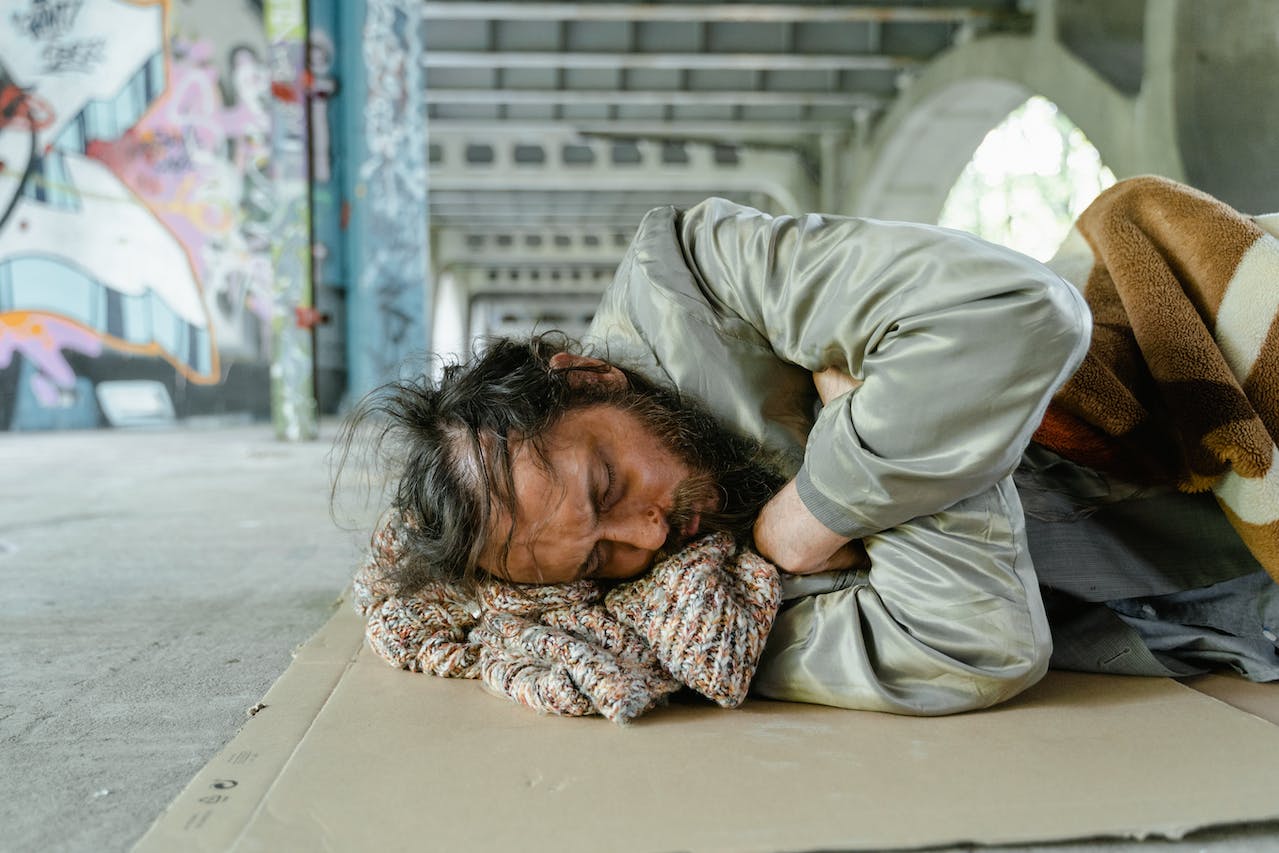 Poor man sleeping on the ground outside.