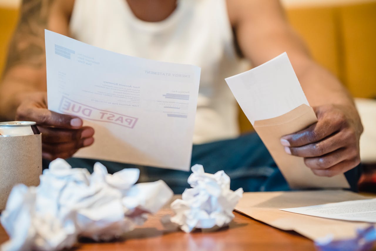 Man sitting by a coffee table looking at bills.
