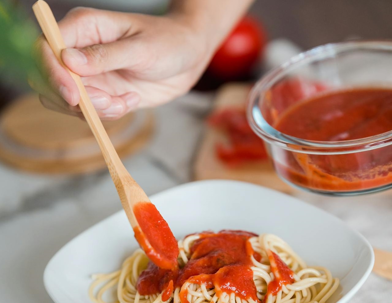 A Person Putting Tomato Sauce in a Pasta