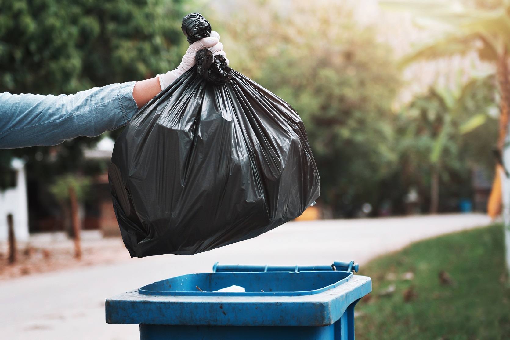 hand holding garbage black bag putting in to trash