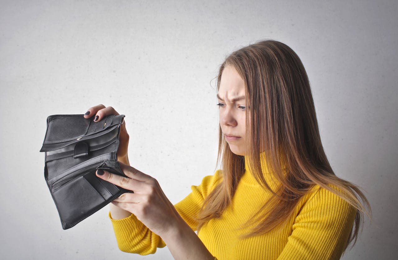 Close-up Photo of a Woman in yellow turtleneck Holding Black Wallet