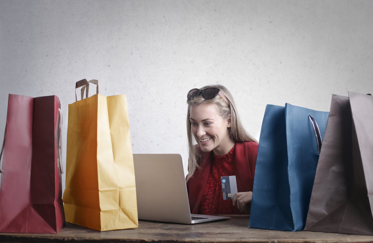 Happy woman shopping online at home, laptop and shopping bags placed on a wooden table