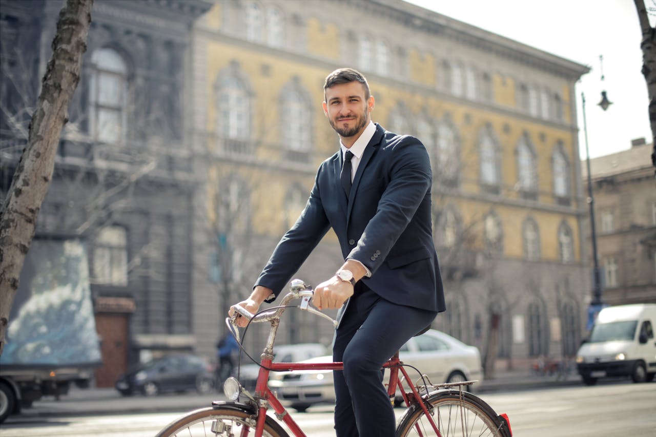 Man in Black Suit Jacket and Black Pants While Riding a Red Bicycle
