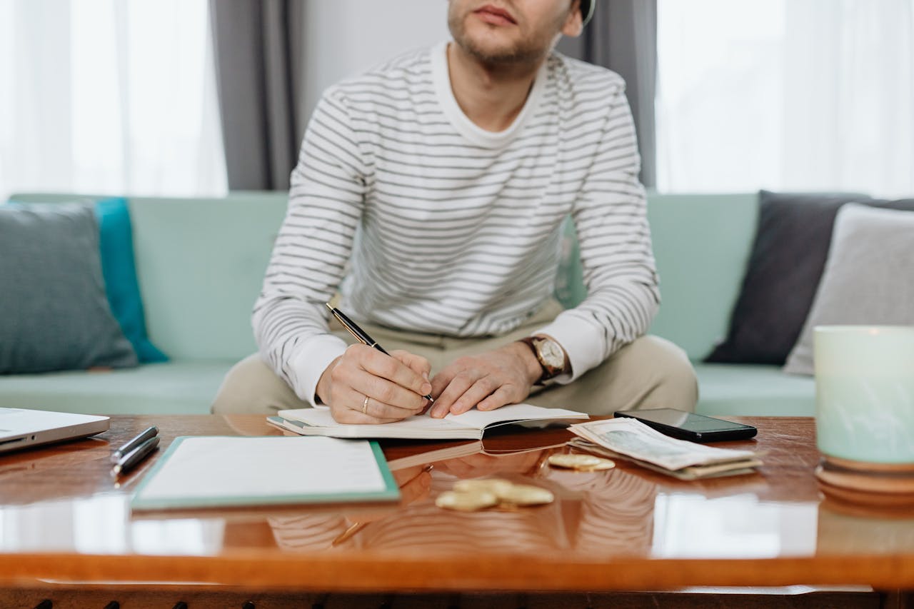 Man in white and gray striped long sleeve shirt sitting at the table doing budgeting