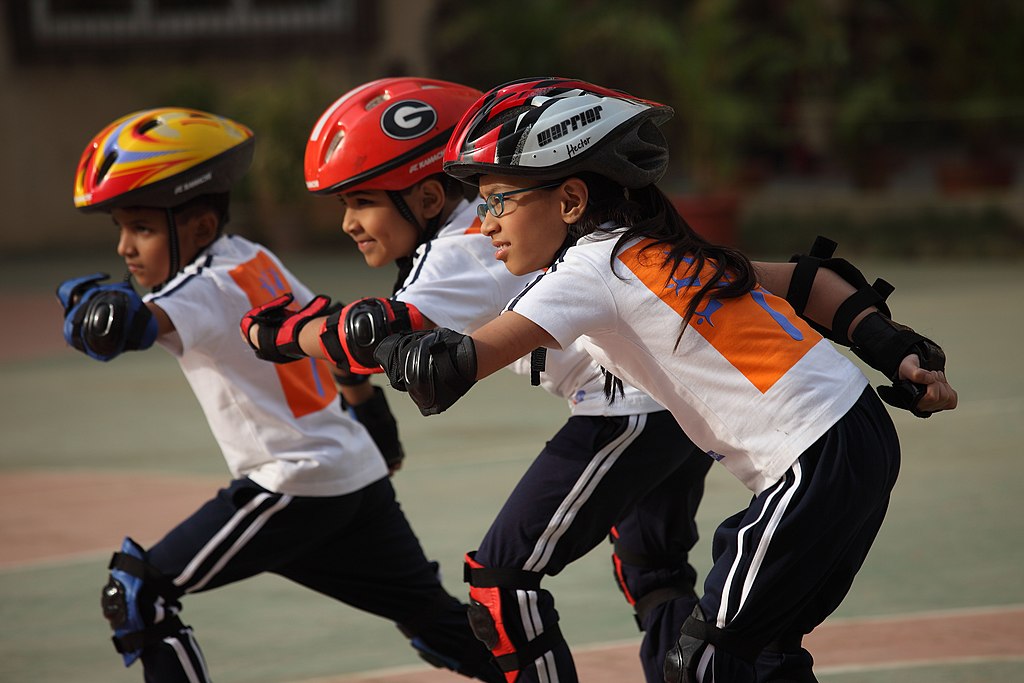 Three Children wearing safety helmets and safety gear doing Extra curricular activities
